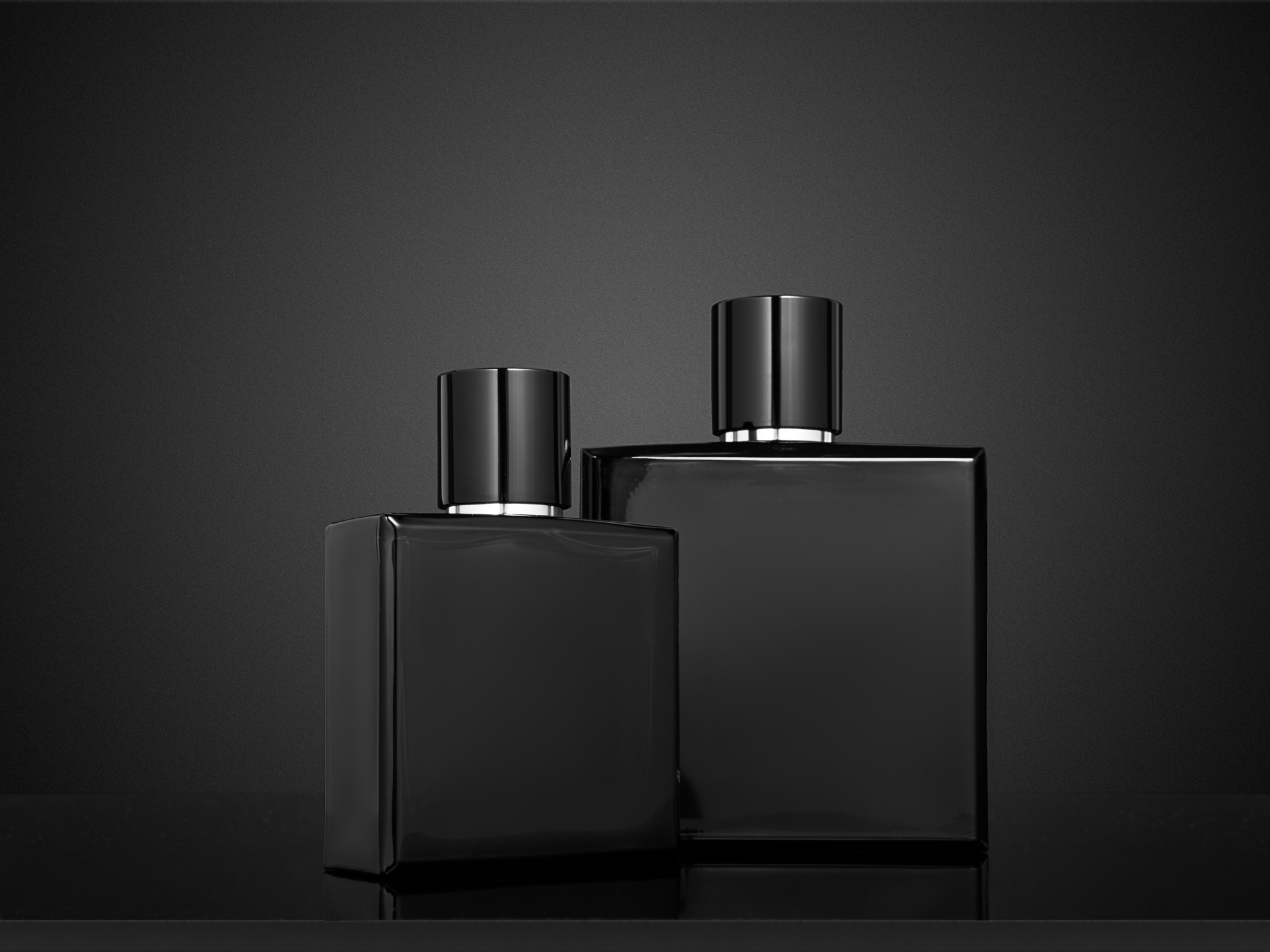 czarne butelki z perfumami na czarnym tle